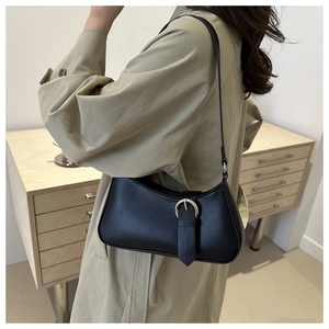 Detail of minimalist black crescent shoulder bag featuring silver buckle and matte leather finish