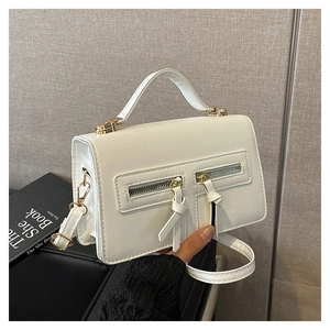 Detailansicht der weißen quadratischen Handtasche mit Doppelreißverschluss und Golddekor