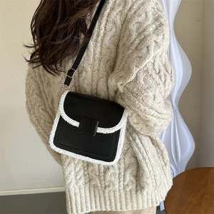 Chic black leather crossbody square bag with white faux shearling trim worn by a model