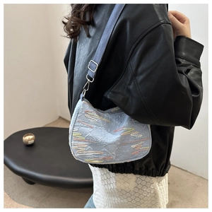 Gros plan du sac à bandoulière bleu clair à motifs porté par un mannequin