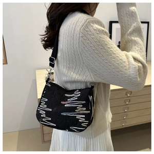 Détail du sac dumpling en toile noire avec broderie ondulée colorée et bandoulière
