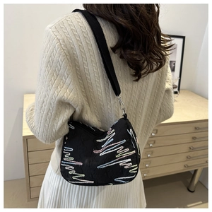Détail d'un sac à bandoulière matelassé avec broderie zigzag colorée et sangle large