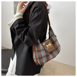 Detail of plaid tote bag featuring leather flap with cartoon dog and top zipper closure