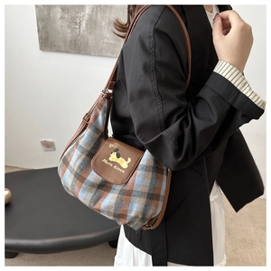 Detailed view of the blue and brown plaid fabric texture and leather flap with dog print