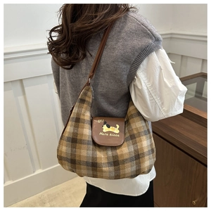 Close-up of vintage plaid hobo bag featuring a brown leather flap with cartoon dog detail