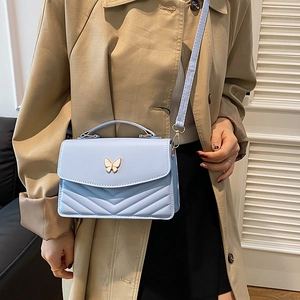 Sky blue quilted crossbody bag for women featuring a gold butterfly buckle accent