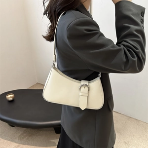 Chic cream white crescent underarm bag with silver buckle worn by a model in casual style