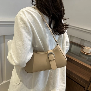 Minimalist beige leather baguette shoulder bag with silver buckle and half-moon silhouette