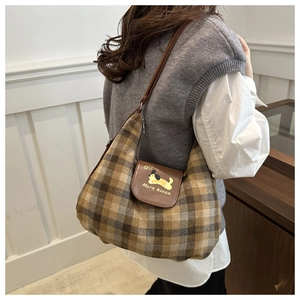 Detail of checkered hobo bag featuring cartoon puppy motif and brown leather strap