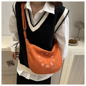 Détail du sac croissant en velours côtelé orange avec broderie de lettres blanches