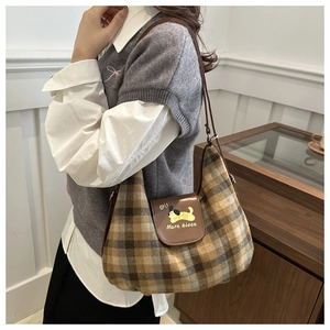 Detail view of plaid underarm bag with leather strap and cartoon dog embroidery