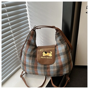 Detail of plaid fabric shoulder bag with leather flap and cartoon dog print