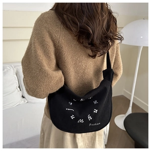 Détail d'un sac hobo en velours côtelé noir avec broderie de lettres et texte fashion