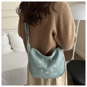 Détail de la besace demi-lune en velours côtelé vert menthe avec broderie blanche