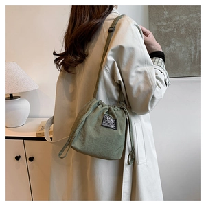 Detail of green canvas bucket bag featuring drawstring closure and fashion tag detail