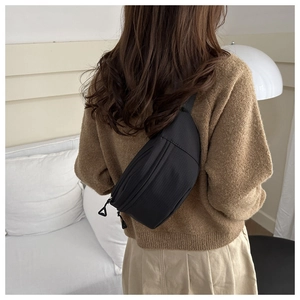 Detail of black nylon crossbody bag featuring multi-layer zippers and unique triangle pulls