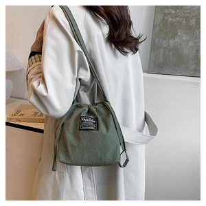 Close-up of a green nylon drawstring bucket bag with a fashion instinct label detail