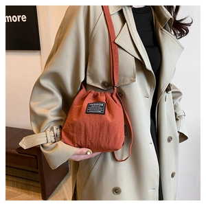 Detail of red-brown nylon bucket bag with drawstring and Fashion Instinct label
