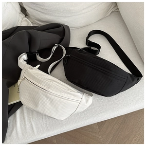 Detail of minimalist crossbody bags in black and white with adjustable straps on soft surface
