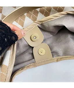 Close-up of golden magnetic closure on khaki lattice knit tote bag with leather trim