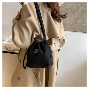 Detail of black canvas bucket bag with drawstring closure and fashion instinct label