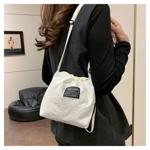 Detailed back view of a white drawstring bucket bag with a black fashion logo patch