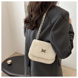 Detail of elegant cream marble-patterned handbag with a decorative metal butterfly clasp
