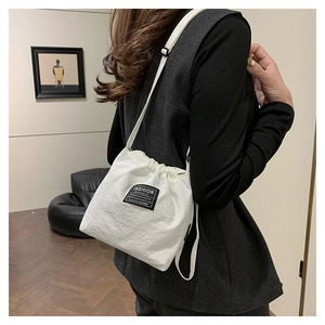 Rear view of a model wearing a white nylon drawstring bucket bag with a fashion logo tag