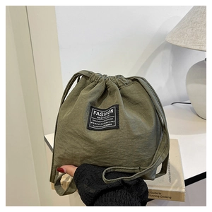 Detail of army green drawstring bucket bag with branded label and textured fabric