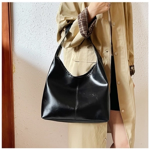Detail of black glossy Hobo bag with vertical stitching and seamless handle on a model