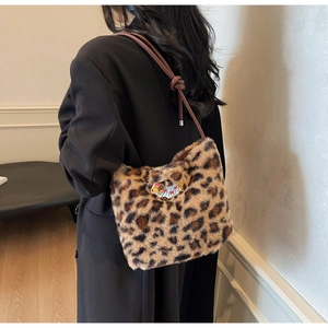 Detail view of leopard print faux fur shoulder bag with animal patch and knotted leather strap