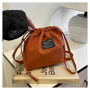 Detail of orange nylon drawstring bag with small square label on a book background