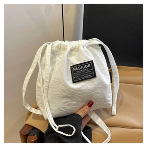 Detail of white drawstring bucket bag with a black and white Fashion Instinct woven label