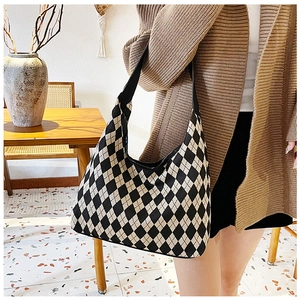 Close-up of a stylish black and white checkered hobo bag worn by a model in a cafe