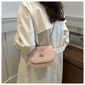 Pink crossbody bag with silver butterfly buckle and leather chain strap on a model