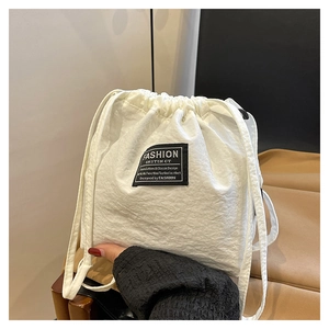 Detail of white drawstring bucket bag showing high-density fabric texture and black label