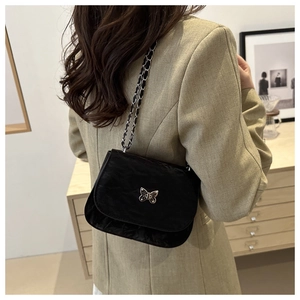Detail of a black wrinkled leather shoulder bag with a silver butterfly buckle and chain strap