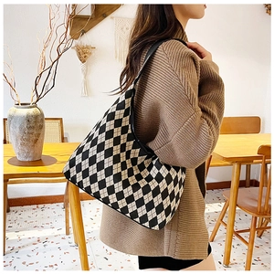 Close-up of stylish black and beige checkered knit hobo bag worn by a model
