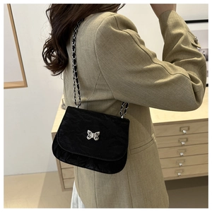 Detail of black pleated crossbody bag with silver butterfly clasp and metal chain strap