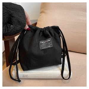 Detail of a black canvas bucket bag with drawstring closure and white fabric label