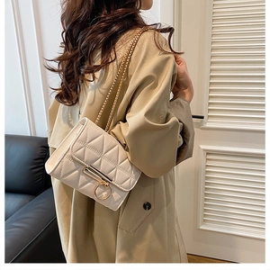 Close-up of white quilted crossbody bag with gold ring lock and elegant chain strap