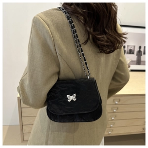 Detail of black pleated shoulder bag with silver butterfly buckle and chain strap