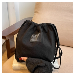 Detailed view of black canvas bucket bag with Fashion Instinct label on white books