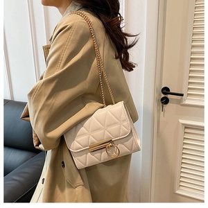Detail of white quilted crossbody bag with gold chain strap and metallic buckle