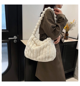 Detail of white faux fur shoulder bag with soft pleated texture and plush ball strap