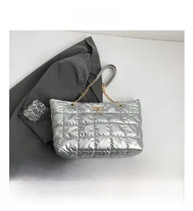 Detail of silver quilted tote bag with metallic finish and gold chain shoulder strap