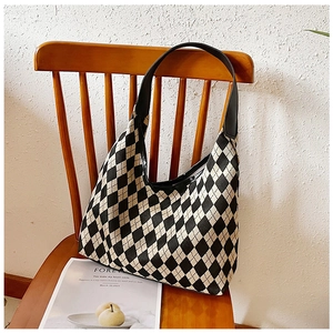 Detail of checkered knit tote bag hanging on a dark wooden chair in a bright room
