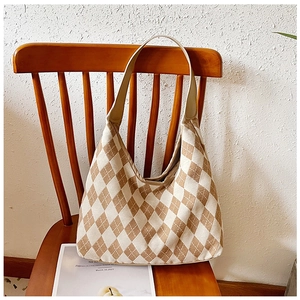 Close-up of vintage argyle hobo bag with wide strap hanging on a wooden chair