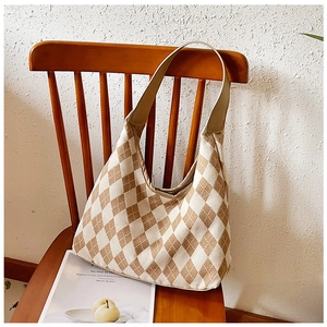 Canvas hobo bag with brown checkerboard pattern draped over a vintage wooden chair