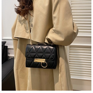 Detail of black quilted leather crossbody bag with golden chain and metallic lock